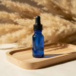 Blue dropper bottle on wooden tray with pampas grass